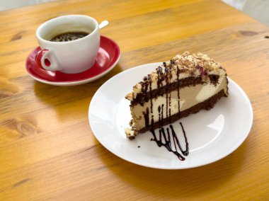 Lezzetli bir dilim çikolatalı kek ve ahşap masa üzerinde kahve..