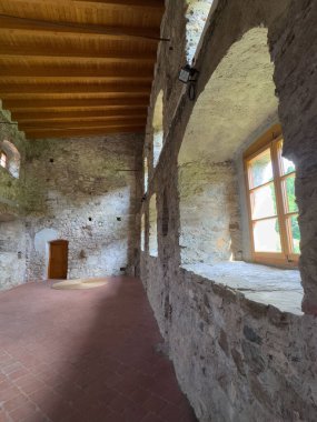 Ahşap tavanı ve kemerli pencereleri olan tarihi binanın içi taştan..