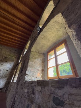 Ahşap tavanlı ve doğanın pencere manzaralı güneş ışığıyla aydınlatılmış taştan iç döşeme.