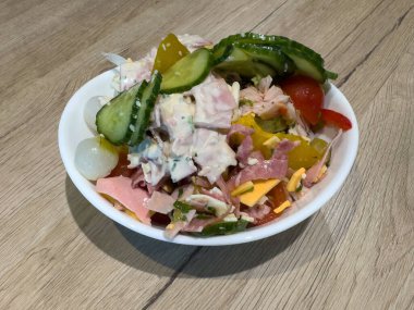 Salatalıklı jambon ve peynir salatası ve ahşap masada beyaz kasede turşu..