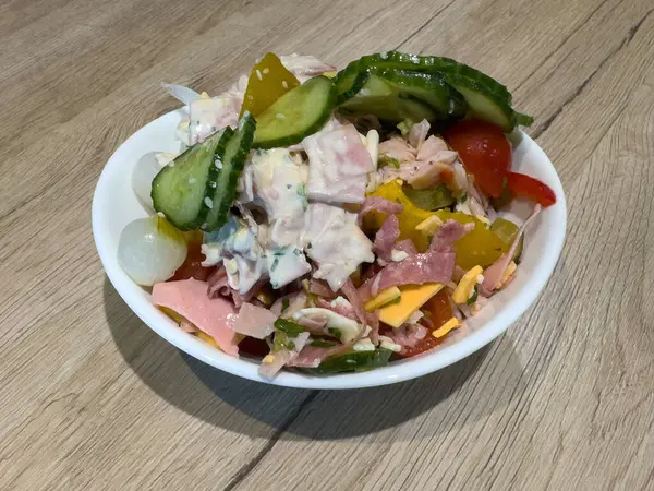 Salatalıklı jambon ve peynir salatası ve ahşap masada beyaz kasede turşu..