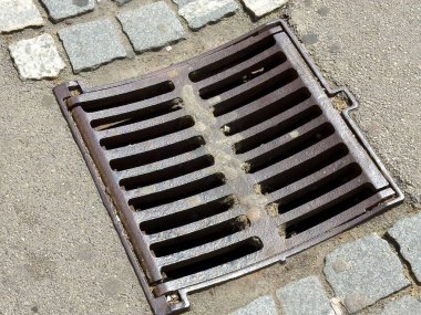 Çakıl taşı sokağında paslı metal yağmur gideri.