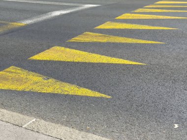 Asfalt yol yüzeyinde çapraz sarı ok işaretleri.