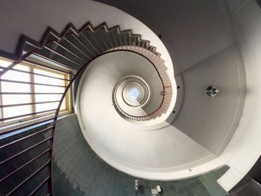 Merkezi ışık kaynağı ve beyaz duvarları olan merdiven içi.