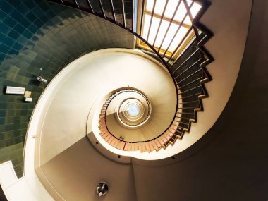 Yeşil kiremitli sarmal merdiven ve pencereden gelen doğal ışık.