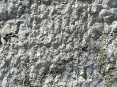 Görünür erozyon desenli yıpranmış gri taş yüzeyinin engebeli dokusu.