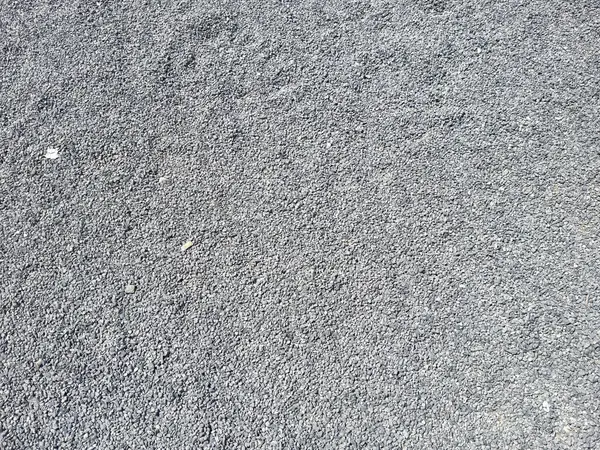 Küçük çakıl taşları ve düz olmayan yüzeyi olan pürüzlü asfalt dokusu.