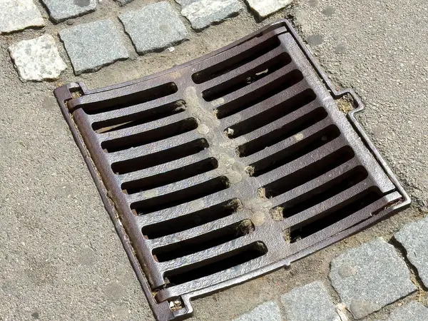 Çakıl taşı sokağında paslı metal yağmur gideri.