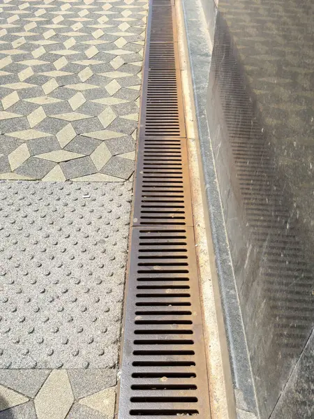 Metal ızgara ve geometrik kaldırım tasarımlı kentsel kaldırım detayı.