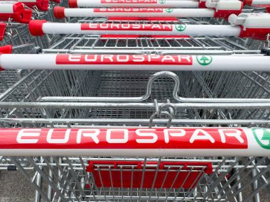 Tarvisio, İtalya - 01 Haziran 2025: EuroSpar alışveriş arabaları parlak renk ve tasarımlarını, perakende kolaylığı ve erişilebilirliği temsil eden, düzenli bir şekilde düzenlenmiştir
