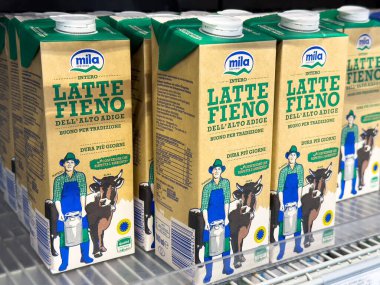 Tarvisio, İtalya - 01 Haziran 2025: Mila marka süt kutuları, soğutmalı bir bölümde Alto Adige saman sütünü vurgulayan geleneksel çiftçi illüstrasyonunu sergiliyor