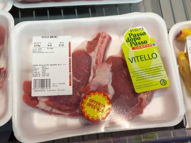 Tarvisio, İtalya - 01 Haziran 2025: Fiyat etiketi ve aşçılık meraklıları için promosyon etiketi bulunan plastik bir tepside taze dana pirzolası sergileniyor