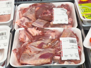 Tarvisio, İtalya - Haziran 01, 2025: Taze domuz pirzolası marketteki beyaz tepsilerde, dokuları ve ambalajları aşçılık amaçlı olarak renklendiriliyor