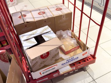 Tarvisio, İtalya - 01 Haziran 2025: Alışveriş arabasında Maxi Hamburger ve Melinda gibi çeşitli yiyecek paketleme kutuları sergileniyor.