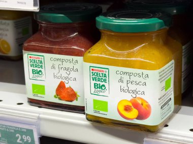 Tarvisio, İtalya - 01 Haziran 2025: Süpermarket raflarında sergilenen organik meyve reçelleri, cam kavanozlarda çilek ve şeftali aromaları
