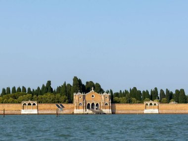 Venedik, İtalya - 25 Haziran 2025: Venedik 'teki ada mezarlığı serin yeşillik ve sakin sularla çevrili çarpıcı bir mimariye sahiptir.