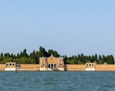 Venedik, İtalya - 25 Haziran 2025: Venedik 'teki adanın tarihi mezarlığı bereketli ağaçlar ve sakin suyla çevrili çarpıcı bir mimariye sahiptir.