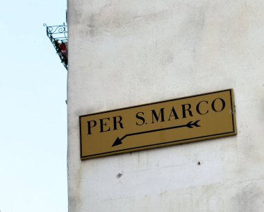 Venedik, İtalya - 25 Haziran 2025: Sokak tabelası San Marco 'yu işaret ediyor, yıpranmış bir duvara asılmış şık harfler ve bir ok.