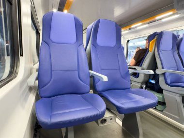 Venedik, İtalya - 23 Haziran 2025: Modern bir iç mekandaki mavi tren koltukları, konfor ve ferahlık için tasarlanmış, yolculuk sırasında yolcu deneyiminin artırılması