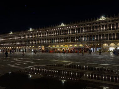 Venedik, İtalya - 23 Haziran 2025: Venedik 'teki St. Mark Meydanı gece çok güzel aydınlatılıyor, ıslak zemindeki yansımalar canlı ambiyansı artırıyor.