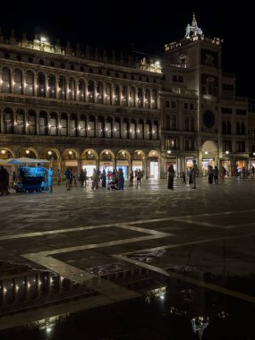 Venedik, İtalya - 23 Haziran 2025: St. Mark Meydanı, Venedik 'teki tarihi binalar, ıslak kaldırıma güzel bir şekilde yansıyarak büyüleyici bir gece sahnesi oluşturdu.