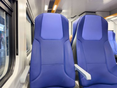 Modern trenin içi parlak ışıkta rahat mavi koltuklarla dolu..