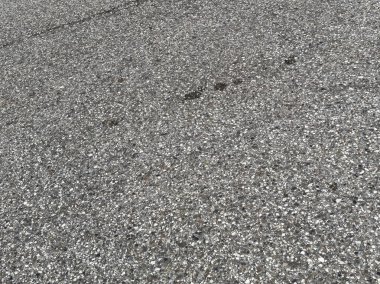 Çakıl taşı desenli gri asfalt kaldırıma yakın çekim.