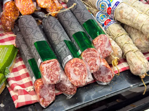 Venedik, İtalya - 23 Haziran 2025: Pazar yerindeki kareli masa örtüsüne yerleştirilmiş paketli salam sosisleri, taze malzemelerin ve geleneksel yöntemlerin altını çiziyor