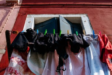 Kırsal pencereli kırmızı binaya karşı renkli çamaşır ipi.