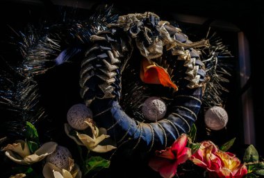 Şenlikli tatil çelengi, süsleri ve çiçekleri gün ışığında..