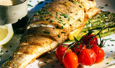 Kuşkonmaz ve soğanla süslenmiş kiraz domatesli ızgara balık..