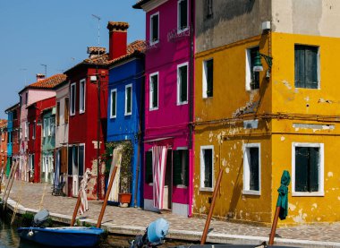 Burano, İtalya - 25 Haziran 2025: Burano, İtalya 'da kanal boyunca canlı evler, suya çok güzel yansıyarak çarpıcı bir görsel atmosfer yaratıyor.