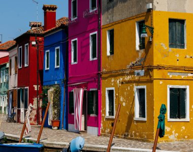 Burano, İtalya - 25 Haziran 2025: Burano, İtalya 'da kanal boyunca canlı evler, suya güzel yansıyarak çarpıcı bir görsel atmosfer yaratıyor.
