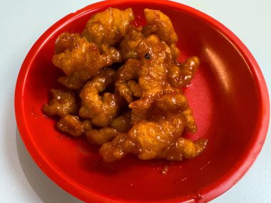 Kırmızı tabakta tatlı ve baharatlı ballı tavuk.