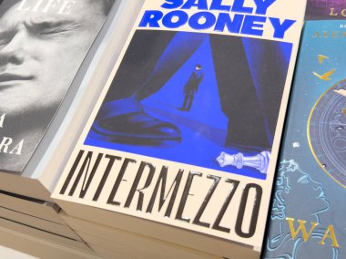 Villach, Avusturya - 01 Temmuz 2025: Sally Rooney 'nin Intermezzo kitap kapağı okuyucular ve koleksiyoncular için ideal bir şekil ve satranç taşlarıyla büyüleyici bir mavi ve siyah tasarım sergiliyor