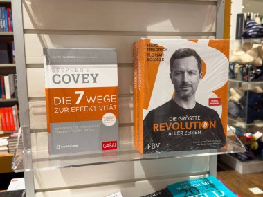 Villach, Avusturya - 01 Temmuz 2025: Bir kitapçıda raftaki kitaplar arasında Stephen R. Covey 'in çalışması ve Marc Friedrich' in popüler kişisel gelişim edebiyatının altını çizen başlığı yer alıyor.