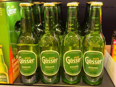 Villach, Avusturya - 01 Temmuz 2025: Gosser Marzen bira şişeleri belirgin bir perakende ortamında sergilenerek, belirgin yeşil cam ve markalaşmalarını vurguluyor