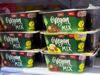 Villach, Avusturya - 01 Temmuz 2025: Muller Vegan Karışık tatlı fincanları, canlı ambalajlar ve cazip aromalar eşliğinde bir süpermarket buzdolabında düzenlenmiştir.