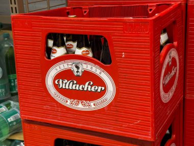 Villach, Avusturya - 01 Temmuz 2025: Kilaucher bira şişeleri içeren kırmızı sandık, bir perakende seti içinde markalaşma ve ambalajı vurguluyor