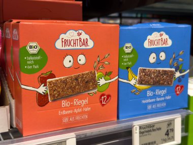 Villach, Avusturya - 01 Temmuz 2025: FruchtBar organik abur cubur barları renkli ambalajlar ve çekici karakter tasarımları vurgulanarak bir süpermarket rafında sergileniyor
