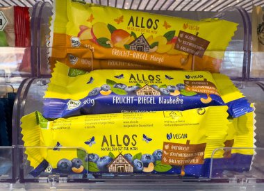 Villach, Avusturya - 01 Temmuz 2025: Mango ve yaban mersini aromalı allos meyveleri, renkli ambalajlarını vurgulayarak temiz bir kapta düzenlenmiştir