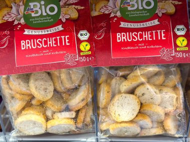 Villach, Avusturya - 01 Temmuz 2025: Organik bruschetta atıştırmalık paketleri bir mağazada sergileniyor, sarımsak ve otlar vurgulanıyor, sağlık bilincine sahip bireyler için mükemmel