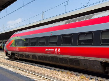 Üstat, İtalya - 25 Haziran 2025: Frecciarossa yüksek hızlı treni, aerodinamik şeklini ve parlak kırmızı dış görünüşünü vurgulayan çağdaş bir demiryolu platformunda konuşlandırılmıştır.