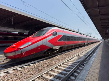 Üstat, İtalya - 25 Haziran 2025: Yüksek hızlı kırmızı tren, aerodinamik biçimini ve modern özelliklerini vurgulayan çağdaş bir tren istasyonuna park edilmiştir.