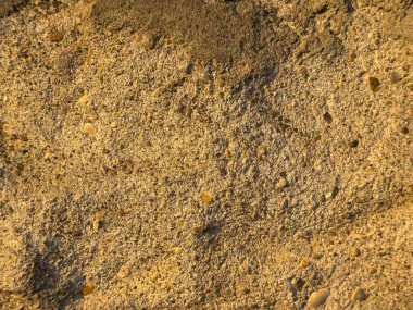 Küçük çakıl taşlarıyla kumlu plaj dokusuna yakın çekim.