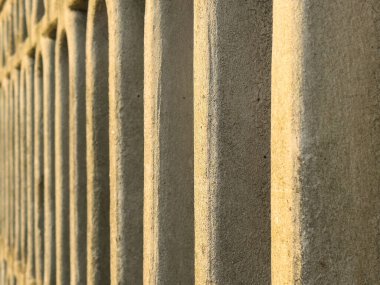 Güneş ışığında tekrarlanan desenli dokulu taş duvarın yakın plan görüntüsü.