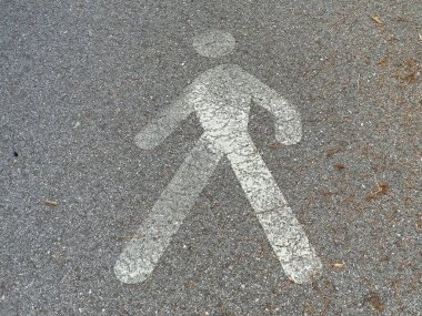 Asfalt üzerinde yapraklar ve dallarla solmuş yaya sembolü.