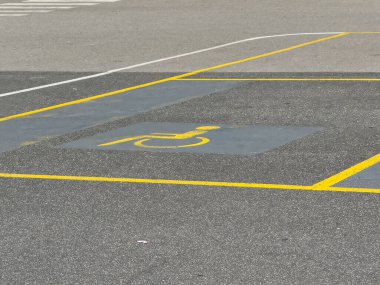 Asfalt yüzeyinde sarı işaretli boş erişilebilir park yeri.