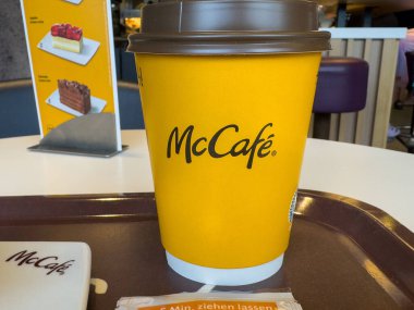 Ljubljana, Slovenya - Temmuz 06, 2025: Fast food restoranında masaya konan McCafe kahve fincanı, açık sarı rengini ve samimi ambiyansını vurguluyor