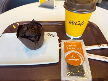 Ljubljana, Slovenya - Temmuz 06, 2025: McKafe kahvesi mükemmel bir kahvaltı ortamı için çay poşeti ve şeker paketleri içeren tepside çikolatalı kek eşleştirildi